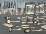 un grand nombre de cuillères et de fourchettes en argent disposées sur une table