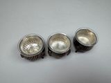 three silver metal bowls sitting on top of a white table