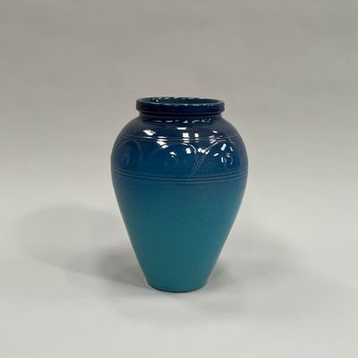un vase bleu posé sur une surface blanche