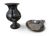 un vase en argent à côté d'une cuillère en argent, posé sur une surface blanche