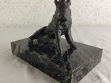 statue of a dog sitting on a marble base on a white surface