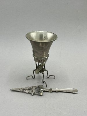 a small silver cup and a knife on a stand