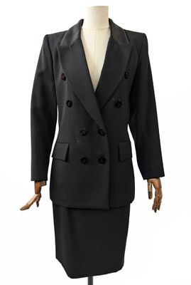 Le costume est noir et comporte des boutons sur le devant.