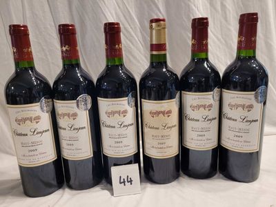 six bottles of red wine are lined up on a table