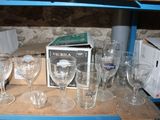 bottles and glasses on a shelf in a room with a stone wall