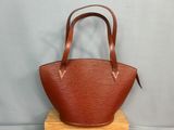 un sac à main en cuir marron posé sur un support en bois