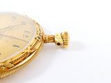 a close up of a pocket watch on a white surface