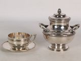 une théière en argent et une tasse en argent posées sur une table
