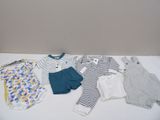 Plusieurs vêtements pour bébé sont disposés sur une table blanche
