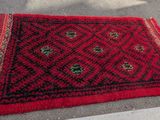 le tapis posé au sol est rouge et noir, avec un motif en losanges