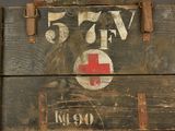 an old wooden box with a red cross sign on it