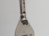 a close up of a spoon on a white surface with a black dot on it