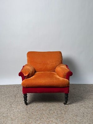 une chaise orange sur laquelle est posé un coussin, dans une pièce