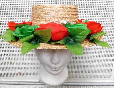 chapeau de paille beige orné de roses rouges et de feuilles vertes