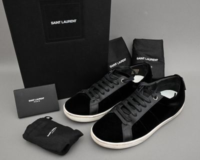 des baskets noires et blanches, avec une boîte noire et un sac noir