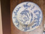 a blue and white plate hanging on a wooden wall