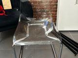 a clear plastic chair and a black chair on the floor
