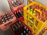 Plusieurs caisses de bière sont empilées les unes à côté des autres sur le sol.