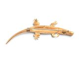 a gold lizard brooch on a white background