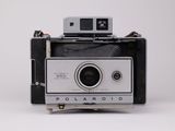 un appareil photo Polaroid posé sur une table blanche