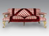 un canapé à carreaux rouges et blancs, avec des pieds dorés et des coussins
