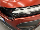 the front end of a red car with a denting dent on it ' s bumper