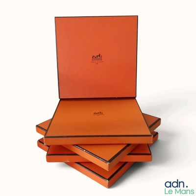 trois boîtes orange sont empilées les unes sur les autres sur une surface blanche