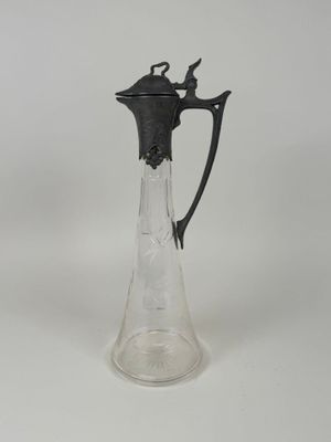 a glass pitcher with a black handle on a white table