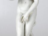 statue d'une femme tenant un chien dans ses bras, posée sur un socle blanc