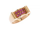 un gros plan d'une bague en or sertie de pierres roses sur fond blanc