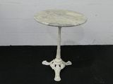 une petite table blanche avec un plateau en marbre posée sur un sol noir