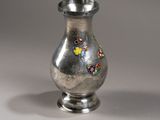 un vase en argent orné de fleurs, posé sur une table
