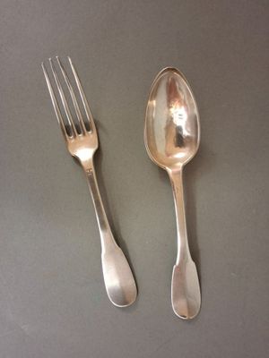 two silver spoons and a fork on a table