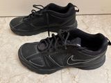 pair of black sneakers with black laces on them on a tile floor