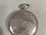 a silver pocket watch sitting on a table next to another pocket watch