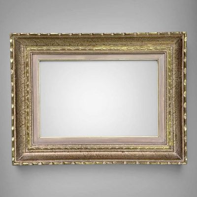 an empty gold frame hanging on a gray wall