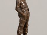 bronze statue of a man standing on a pedestal with his hands in his pockets