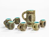 five mugs and a pitcher sitting on a white surface