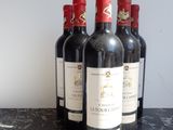 four bottles of red wine are lined up on a table