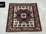 un vieux tapis est exposé sur une surface blanche