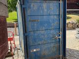 des toilettes portables bleues posées au milieu d'un terrain en terre battue