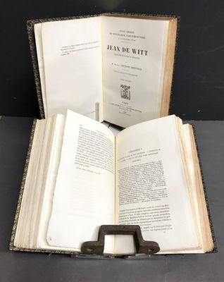 un livre ouvert posé sur une table, à côté d'un support métallique