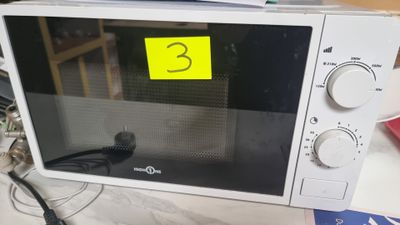 a microwave that is sitting on a table with a yellow sticker on it