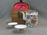 a tea pot and two cups sitting next to a basket