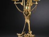 un candélabre ancien en laiton à quatre bougies, posé sur un socle en marbre