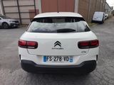 the rear end of a white car parked in a parking lot