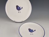 two plates with birds painted on them sitting on a table