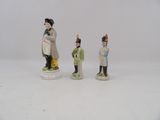 three figurines of men dressed in military uniforms stand in front of a white background