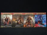 Trois livres de la série Warhammer sont alignés sur une surface noire