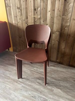 une chaise en plastique marron posée devant un mur en bois